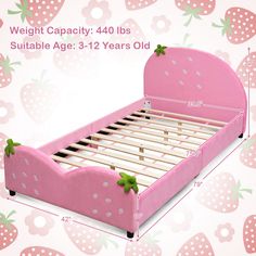 a pink bed with wooden slats and green bows on the headboard is shown