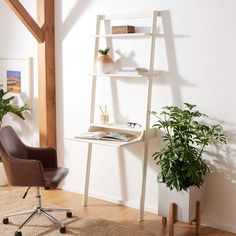 a chair sitting in front of a desk with a computer on it and a potted plant next to it