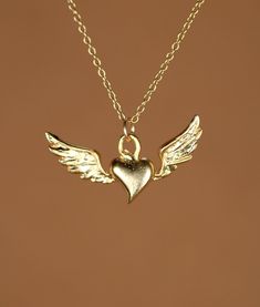 Flying heart necklace, silver heart pendant with wings, wing necklace, a 14k gold vermeil heart and wings on a 14k gold filled chain This super cute and dainty 14k gold plated sterling silver flying heart hangs from a 14k gold filled chain in the length of your choice! This beauty is also available in sterling silver and the pendant measures 22mm x 8mm. Looking for other charm necklaces? https://www.etsy.com/shop/BubuRuby?section_id=12318467 More crystals and healers? http://www.etsy.com/shop/Bu Sterling Silver Gold Angel Wings Jewelry, Gold Sterling Silver Jewelry With Angel Wings, Gold Wing-shaped Sterling Silver Necklace, Gold Winged Sterling Silver Jewelry, Gold Winged Necklace For Gift, Gold Winged Necklace Perfect As A Gift, Elegant Heart-shaped Angel Wings Necklace, Elegant Heart Shaped Angel Wings Necklace, Angel Wings Heart Pendant Jewelry For Gifts