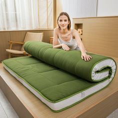 a woman laying on top of a green mattress