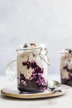 two mason jars filled with blueberry cheesecake and oatmeal toppings