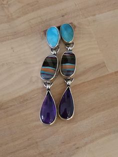 I've used 925 sterling silver.  Then carefully selected gorgeous stones for this design.  I chose a beautiful Kingman turquoise.  And incorporated gorgeous colorful surfite.  Adding a phenomenal genuine amethyst.  The combination is striking.  Giving the design a 70s vibe.  Promoting a fun feel with a unique appeal.  A one-of-a-kind statement.  Lots of movement.  And timeless design.  See pictures for size reference.  Ready to ship! Multicolor Cabochon Gemstones In Sterling Silver, Purple Multi-stone Sterling Silver Earrings, Kingman Turquoise, Amethyst Earrings, Silver Turquoise, Stone Earrings, Turquoise Sterling Silver, Lebanon, Halloween Shopping