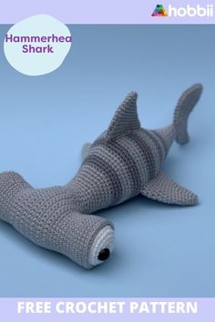 a crocheted shark toy laying on the ground with text overlay that reads hammerhead shark free crochet pattern