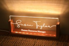 a light up sign with the name susan taylor human resources manager in white on it