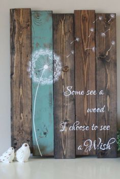 a wooden sign with some dandelions on it and two little birds sitting next to it