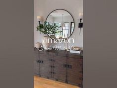 the interior of an elegant home with wood floors and white walls, large round mirror on the wall