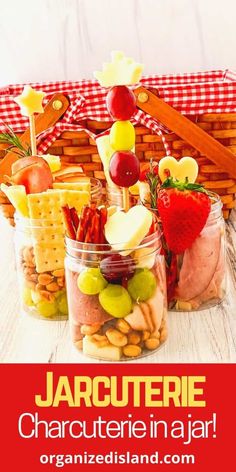 jars filled with fruit and crackers on top of a wooden table next to a picnic basket