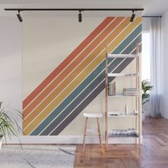 a wall mural with multicolored stripes on it in a living room next to a book shelf