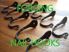 there are many hooks on the table with green lettering that says, forging nail hooks