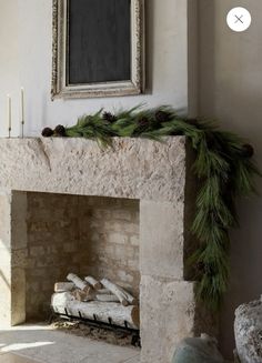 the fireplace is decorated with pine cones and greenery