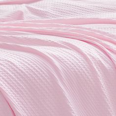 a pink blanket is laying on top of a bed