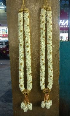 two long white beads hanging from the side of a wall next to a parking meter