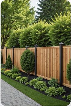 a wooden fence surrounded by lush green trees and shrubbery, along with black edging