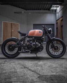 an orange and black motorcycle is parked in a building with wooden doors on the side