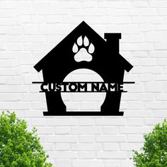 a dog house with paw prints on it and the word custom name in black against a white brick wall