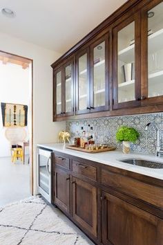 a kitchen with wooden cabinets and white counter tops, along with a rug on the floor