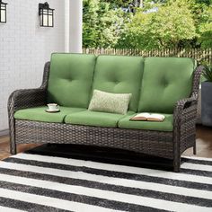 a green couch sitting on top of a wooden floor next to a black and white rug