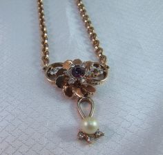 "c1950's, 1940's gold plated fashion necklace/chocker. The necklace is only 15 inches long, very typical of necklaces from this time period The setting and chain is gold palted. The center flower is centered with an amethyst rhinestone surrounded by clear stones. Suspended below is faux pearl, 1/4\" in diameter (6.35mm) No markers identification on the piece." Gold Choker With Flower Charm, Gold Flower Pendant Costume Necklace, 1940s Necklace, Gold Flower-shaped Costume Necklace, 1950s Pearl Necklace, Rhinestone Fashion, Clear Stone, Time Period, Gold Flower