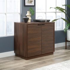 a wooden cabinet sitting in front of a window with potted plants on top of it