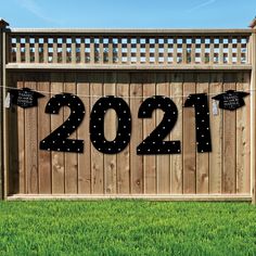 a wooden fence that has some black numbers on it and two signs hanging from the top