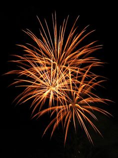 fireworks are lit up in the night sky with bright orange and yellow lights on them