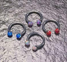 three pairs of fake opal and black metal captive rings with colored balls on them