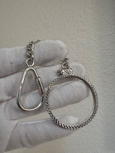 a pair of silver colored metal rings on a white gloved hand, with one being held in the palm