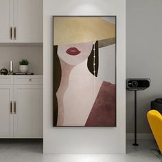 a painting hanging on the wall next to a yellow chair in a room with white cabinets