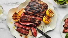 steak and vegetables on plates with utensils next to them, including lemons