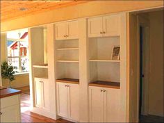 an empty room with white cabinets and wood floors