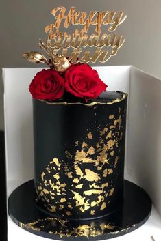 a black and gold birthday cake with red roses