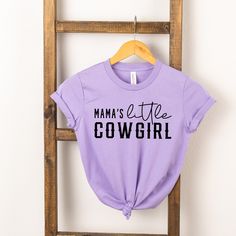 Looking for a cute tee for your kids? We have the perfect Mama's Little Cowgirl graphic tee addition to their closet! Trendy Purple Slogan T-shirt, Spring Lavender Letter Print Top, Casual Lavender T-shirt With Letter Print, Purple Pre-shrunk T-shirt For Spring, Fun Purple T-shirt With Funny Print, Cute Purple Top With Letter Print, Cute Purple Top With Graphic Print, Cute Purple Short Sleeve T-shirt, Cute Purple Spring T-shirt