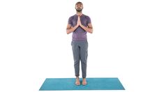 a man standing on a yoga mat with his hands folded in front of his face