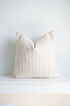 a white pillow sitting on top of a white shelf