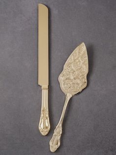 a gold colored knife and fork on a gray surface