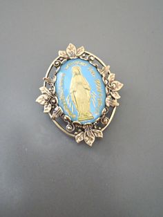 "Vintage Jewelry - Vintage Brass - Blue Brooch - Mother Mary Jewelry - Catholic Brooch - Religious Jewelry - handmade jewelry This is such a pretty brooch! Vintage brass setting embellished with a vintage light blue and gold vintage cameo of the Mother Mary. Exquisite detail with a rich patina on the brass. This is a real special piece. Chloe says, \"Wear it and feel fabulous!\" The pendant is 1 1/4\" long Thanks for visiting Chloe's" Antique Blue Collectible Brooches, Antique Handmade Blue Brooches, Blue Brooch Lapel Pin As Gift, Vintage Blue Enamel Pin Gift, Blue Brooch Pin For Gift, Blue Brooch Pins As A Gift, Blue Brooch Pin As Gift, Blue Brooch Pins For Gift, Mary Jewelry