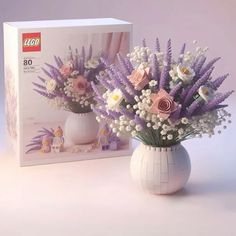 a white vase filled with flowers next to a box of legos set 807