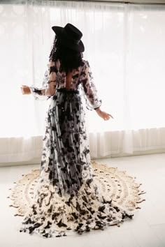 a woman in a black and white dress standing on a doily with her arms outstretched