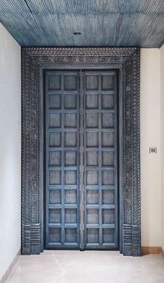 an ornate wooden door in the middle of a room with white walls and flooring