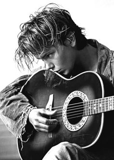 a young man is playing an acoustic guitar