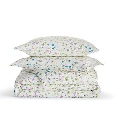 three pillows stacked on top of each other in front of a white background with blue and pink flowers