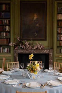 a table set with plates and glasses in front of a fireplace