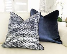 two pillows sitting on top of a white couch