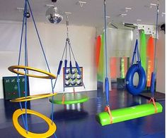 an indoor gym with swings, rings and exercise mats