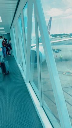 people waiting in line at an airport for their luggage to be loaded into the plane