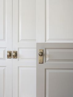 two white doors with brass handles and knobs in a room that is painted white