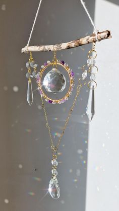 a wind chime hanging from a tree branch with crystal beads and crystals on it