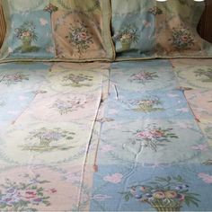 a bed with blue and pink floral bedspread on it's side, next to two pillows