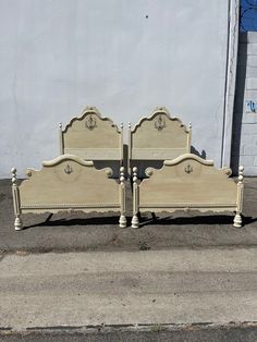 two white beds sitting next to each other on the sidewalk in front of a building