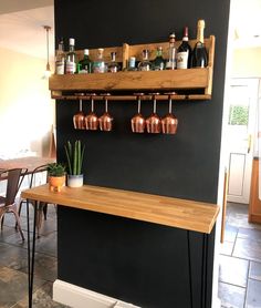 there is a bar with wine glasses on the shelf and bottles hanging from the wall